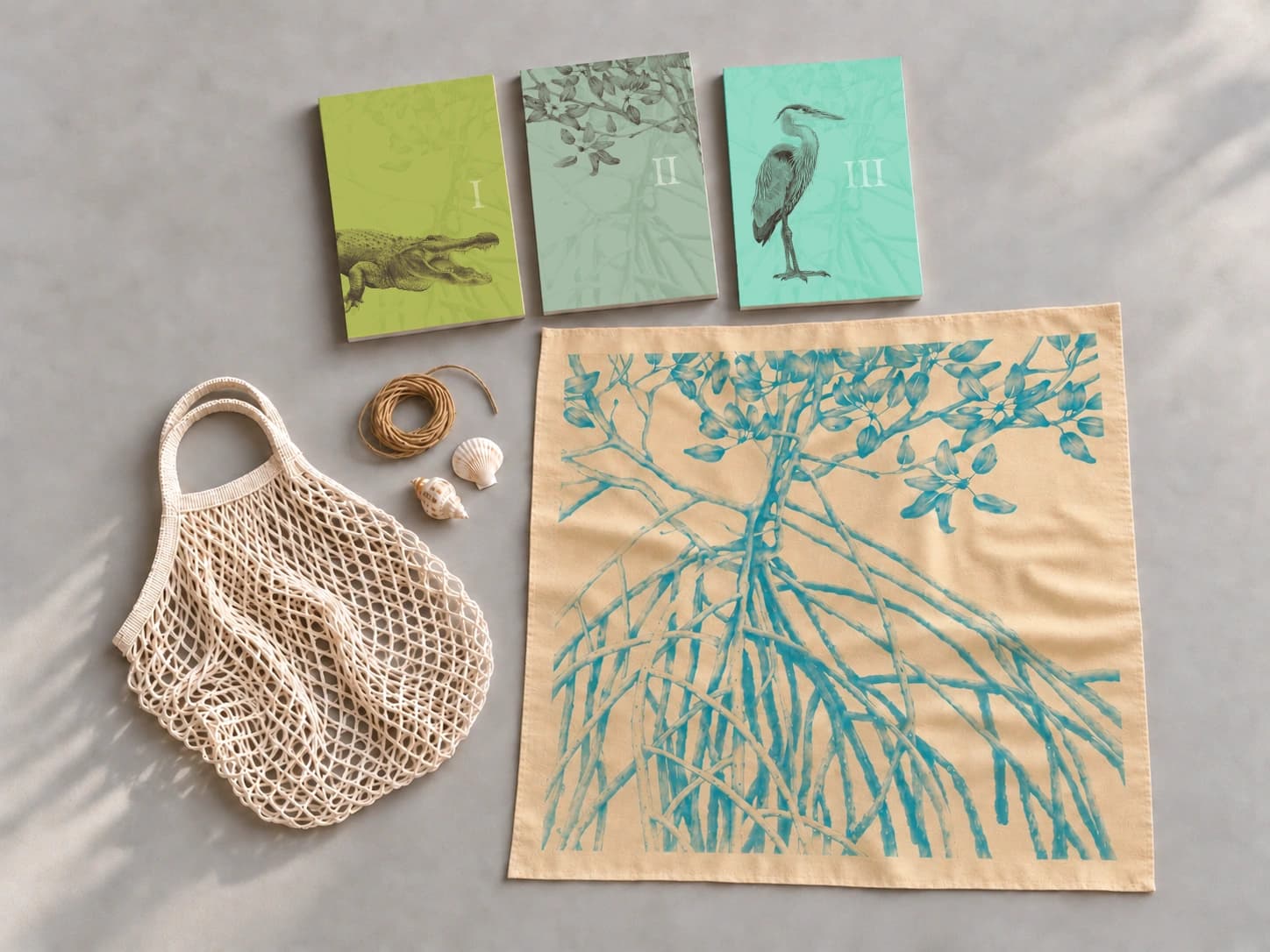 Breakwater Limited Edition set: alligator, mangrove, and heron books with a teal mangrove-print bandana on buff fabric, a natural net bag, hemp twine, and two seashells